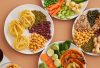 A vibrant mix of legumes, vegetables, nuts, and pasta arranged on white plates showcasing a balanced, healthy diet.